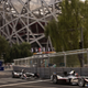 Formula E cars race past the Beijing Olympic Stadium